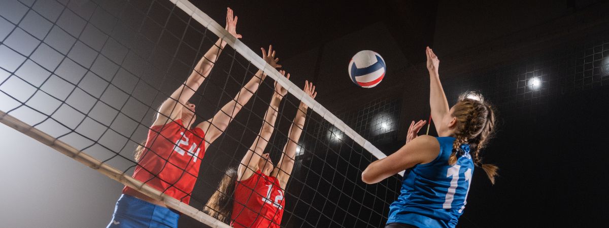 Azione di gioco in una partita di pallavolo con schiacciata e muro a rete